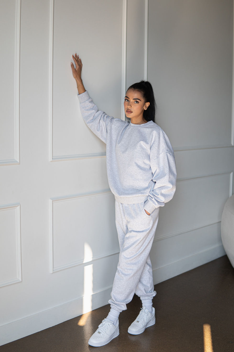 Person in casual outfit leaning against a wall.