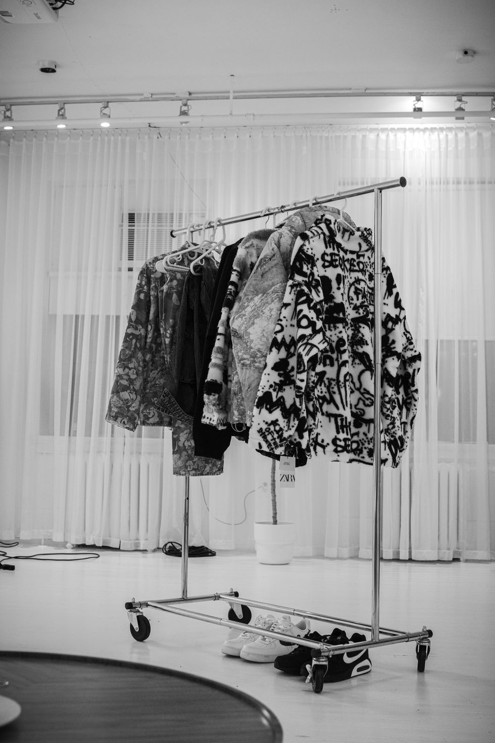 Clothing rack with patterned jackets in a bright room.