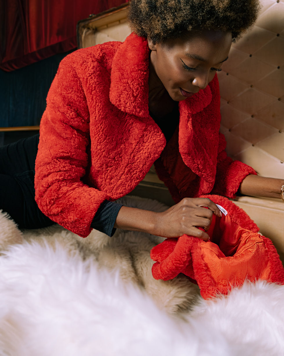 Person in red coat examining fabric indoors.