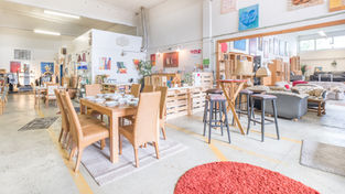 Helle Verkaufsfläche im Sozialkaufhaus Fundus mit Esstischen, Stühlen, Barhockern und Wohnaccessoires