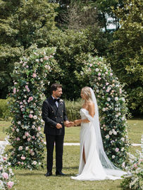 Bride and groom under a flower arch at Château de la Couronne, a fairytale wedding venue in Dordogne, France - Photographer Wedstory Bordeaux.