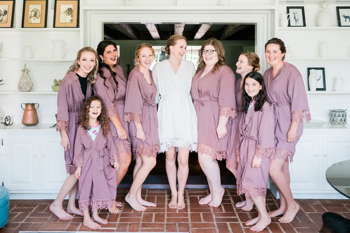 A happy bridal party gathers in the garden room for summer wedding day portraits. 
