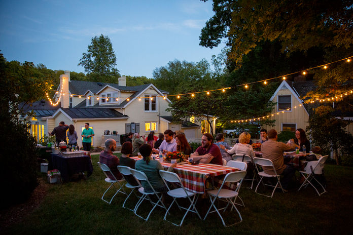 The garden between Spotswood Lodge and Cottage is decorated with hanging twinkling lights, rectangular dinner tables with checkered table cloths and ample seating for this special dinner reception. 