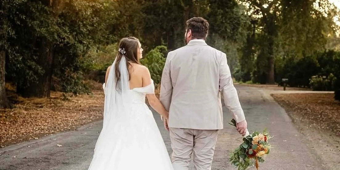 Bride and groom walking hand-in-hand on a path