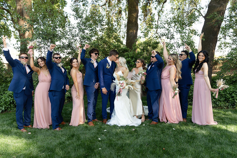 Wedding couple kissing with celebrating wedding party