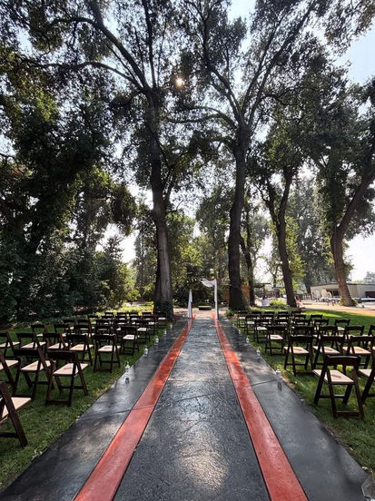Outdoor ceremony aisle with red stripes, chairs, and tall trees