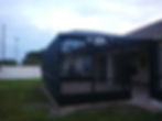 Side view of the dark-framed screen enclosure beside the house — Jeremy's Screen Repair & Handyman Service
