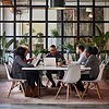 Diverse group of employees collaborating together at a table during a team meeting focused on community healthcare initiatives.