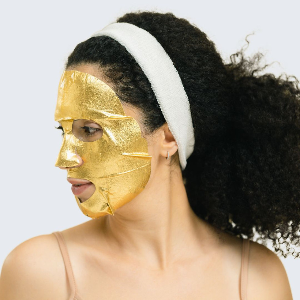 A plush white spa headband on a woman wearing a gold face mask.