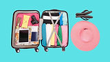Packed suitcase, hat, and flip-flops ready for vacation