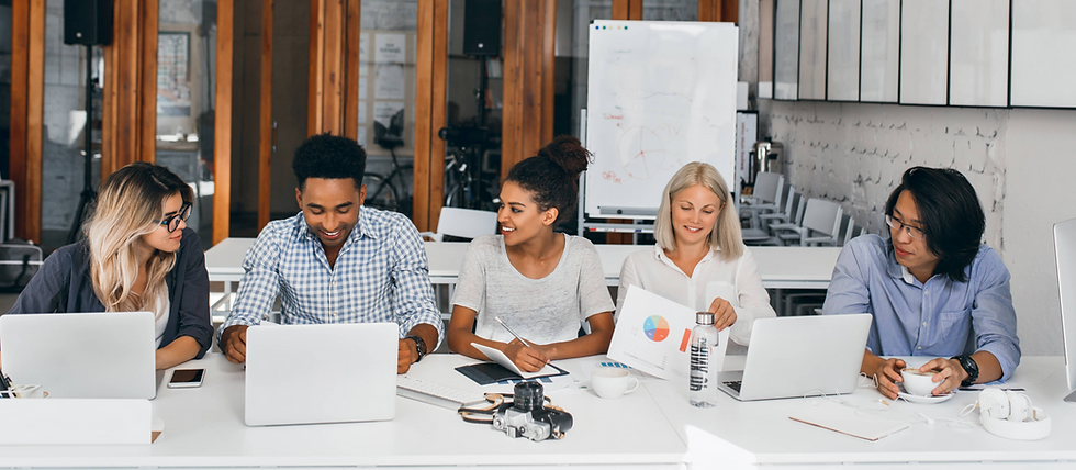 Diverse group of young professionals working together at a desk in a collaborative office environment supporting community health initiatives.