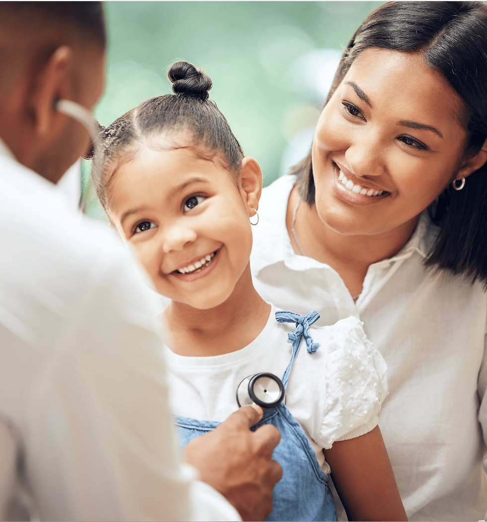 Doctor listening to a young girl’s heartbeat during a pediatric checkup while her Hispanic mother smiles beside her in a healthcare setting.