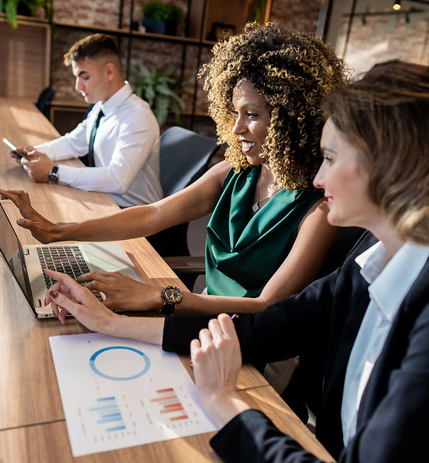 Three professionals collaborating together at a desk during a team meeting in a community healthcare office setting.