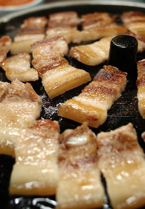 Pork Belly on a grill at a Korean barbeque restaurant.