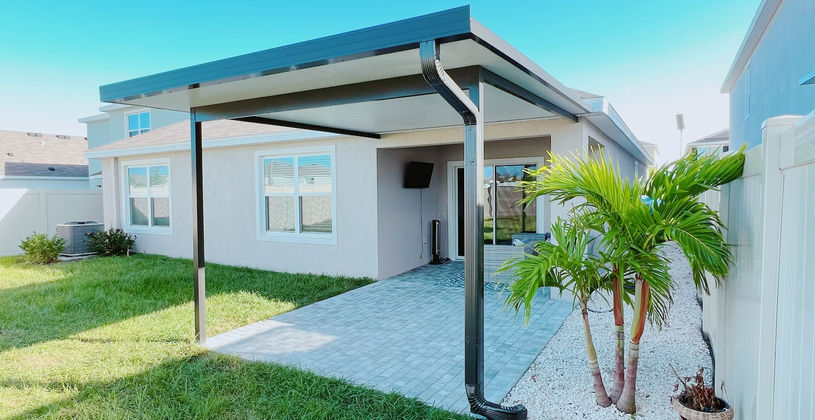 Modern patio cover over a stone backyard patio.