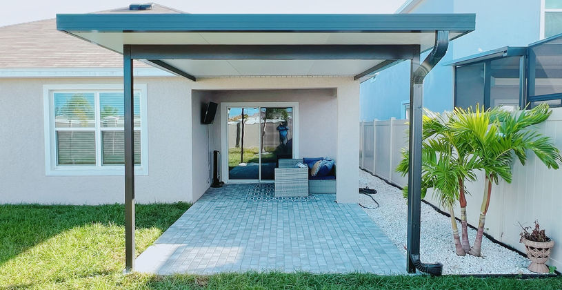 Modern patio cover over a paved backyard lounging area