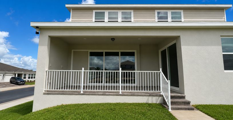 Rear view of modern house with covered porch and white railing
