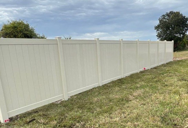 White vinyl privacy fence in a grassy field