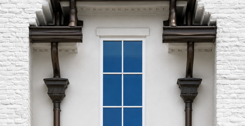 Dark gutters on a white brick house near a window