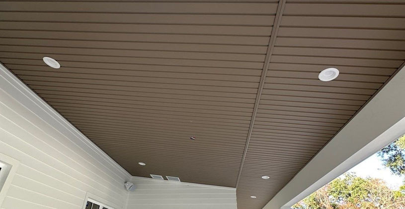 Brown wood-paneled porch ceiling with recessed lighting
