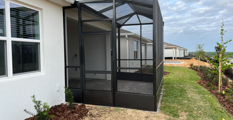 Modern black screened-in patio enclosure on a white house.