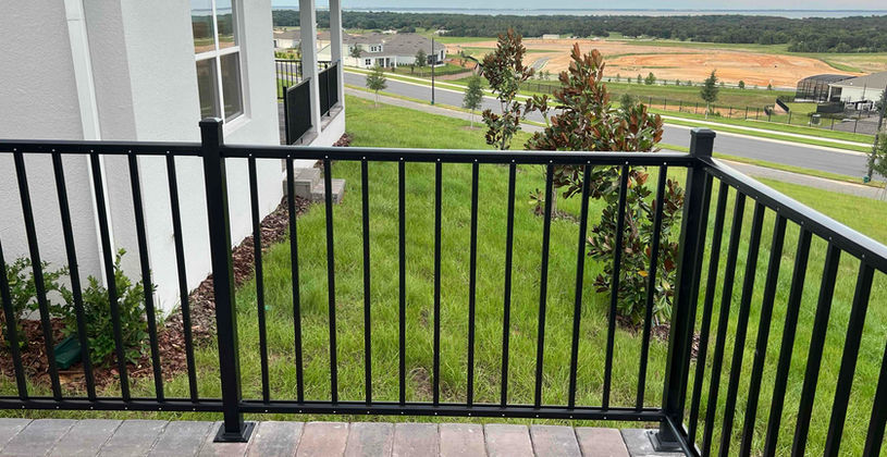 Black aluminum railing on a stone patio overlooking a yard