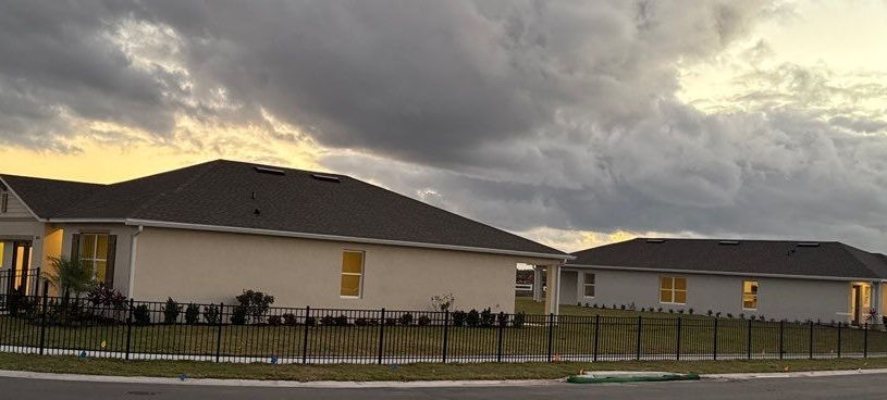 Modern ranch-style homes at dusk under a cloudy sky.