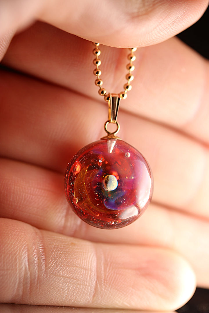 Pendentif rouge et or, orné d'un motif rond et d'une chaîne dorée.