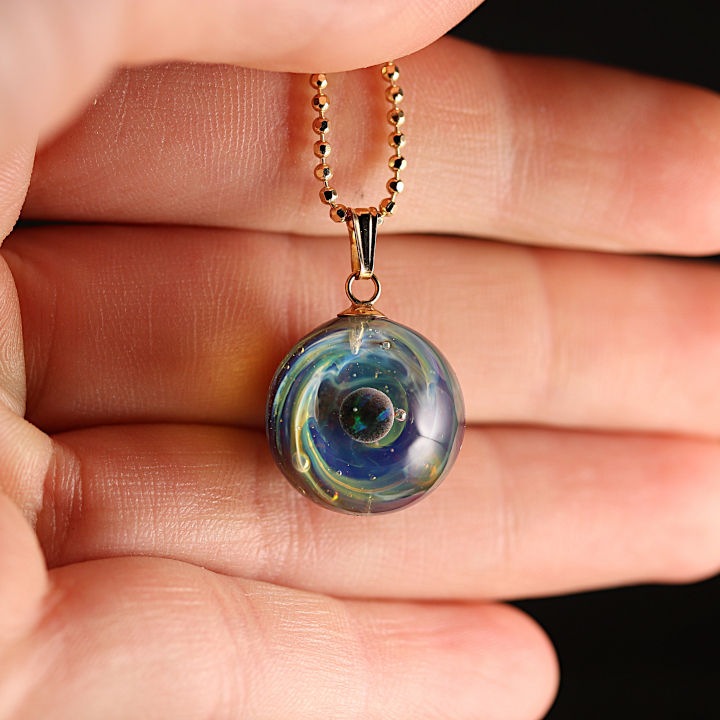 collier galaxie posé sur une mains