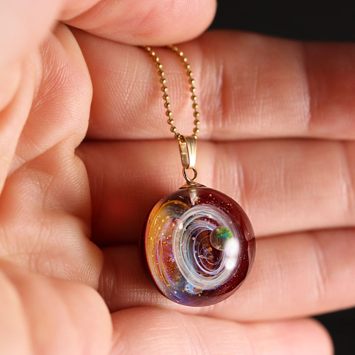 Pendentif rond rouge et or, détail main