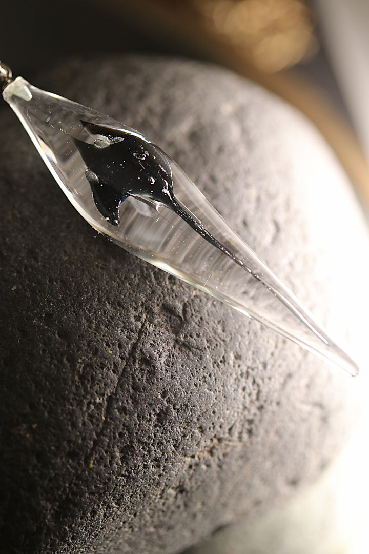 Thumbnail: Une figurine en verre d'une Raie Manta, posée sur une pierre sombre.