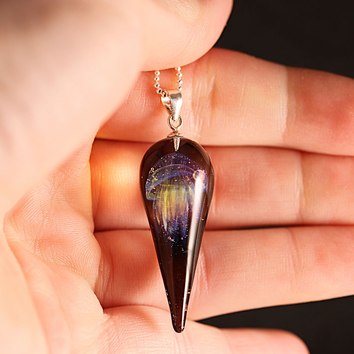 collier méduse de couleur violet et jaune posé sur une mains.