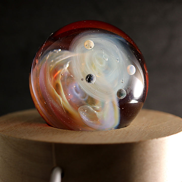 Thumbnail: veilleuse galaxie posé sur un socle en bois.