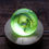 Thumbnail: Boule de Noël en verre soufflée, green glass sphere on a wooden stand glowing.