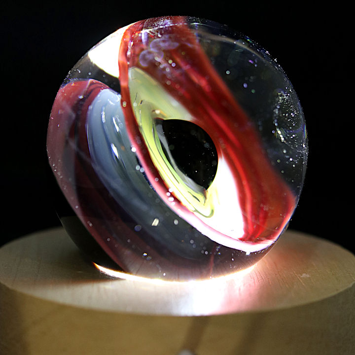 Thumbnail: Veilleuse galaxie trou noir.
sphère en verre qui représente un trou noir de couleur rouge et jaune .