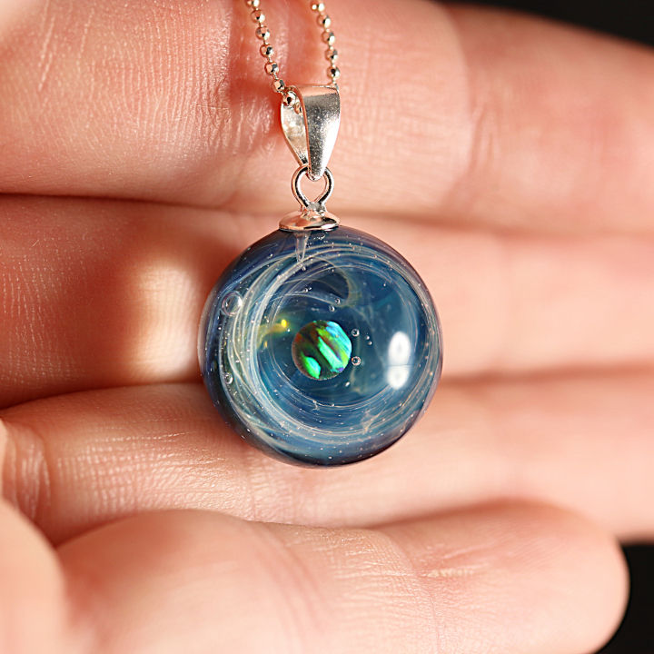 collier galaxie posé sur une mains.