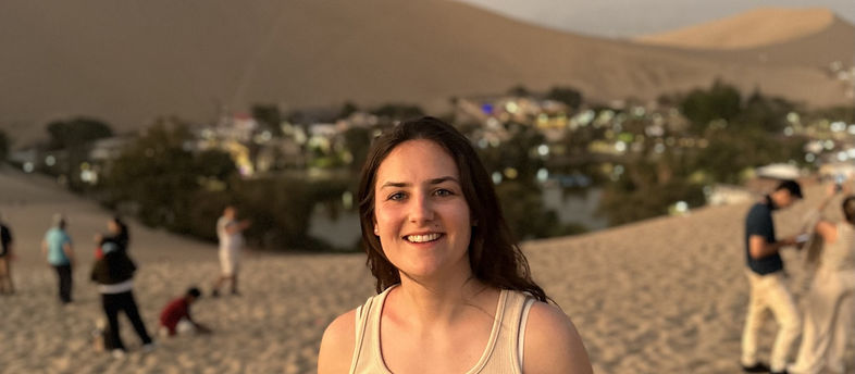 Personne souriante au désert de Huacachina, oasis visible derrière