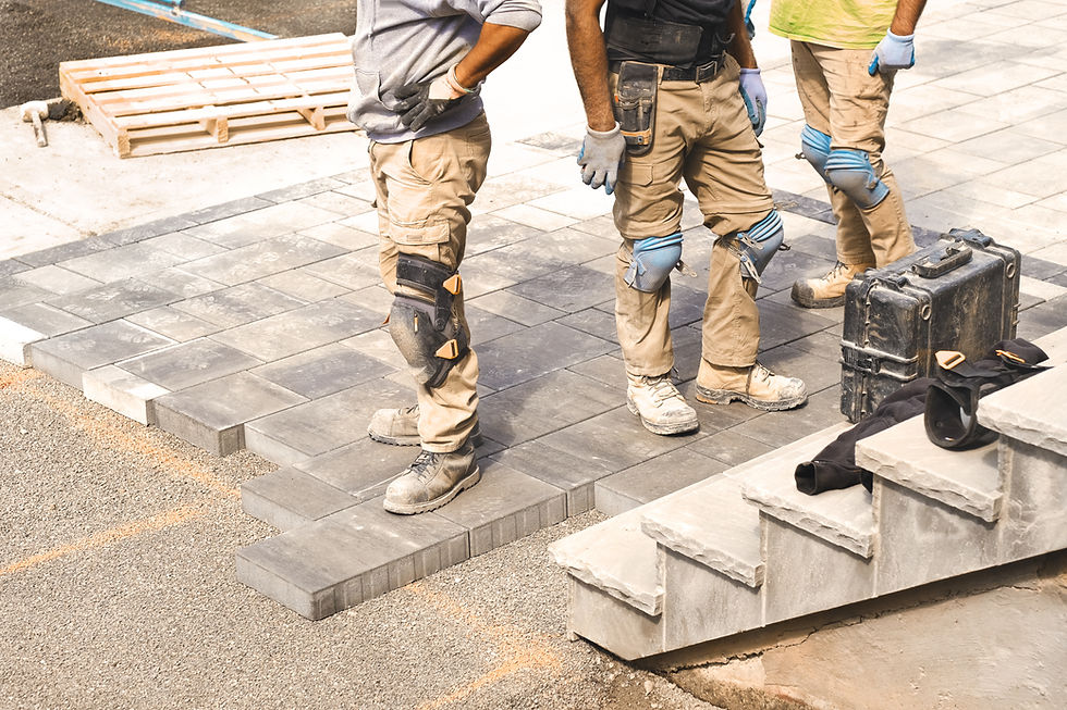 Three construction workers working on landscaping construction site, laying paving drivewa