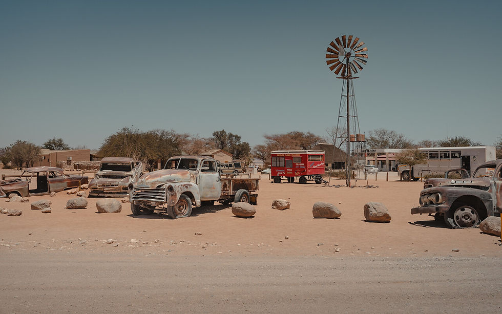 Straße mit kaputten Oldtimern in Namibia nähe Tankstelle und Bäckerei