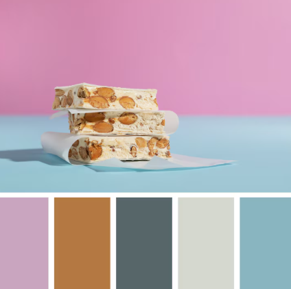 Nougat with nuts on white paper against pink and blue background, below are five color swatches in purple, brown, gray, cream, and blue.