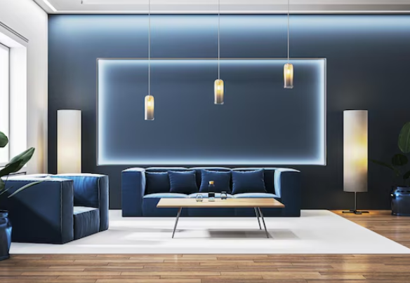 Modern living room with blue walls, a blue sofa, and armchair. Pendant lights hang above a wooden coffee table. Sleek, elegant design.