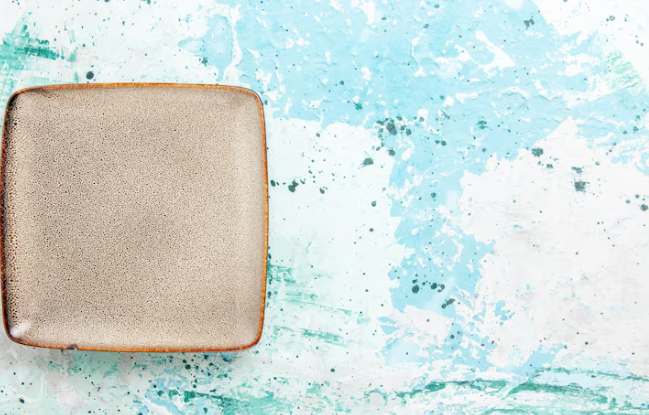 Brown square plate on a blue and white marbled background. The plate is empty, and the scene has a calm, artistic vibe.