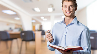 young-male-teacher-standing-with-book.jpg