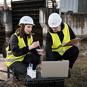 full-shot-smiley-engineers-with-laptop-outdoors.