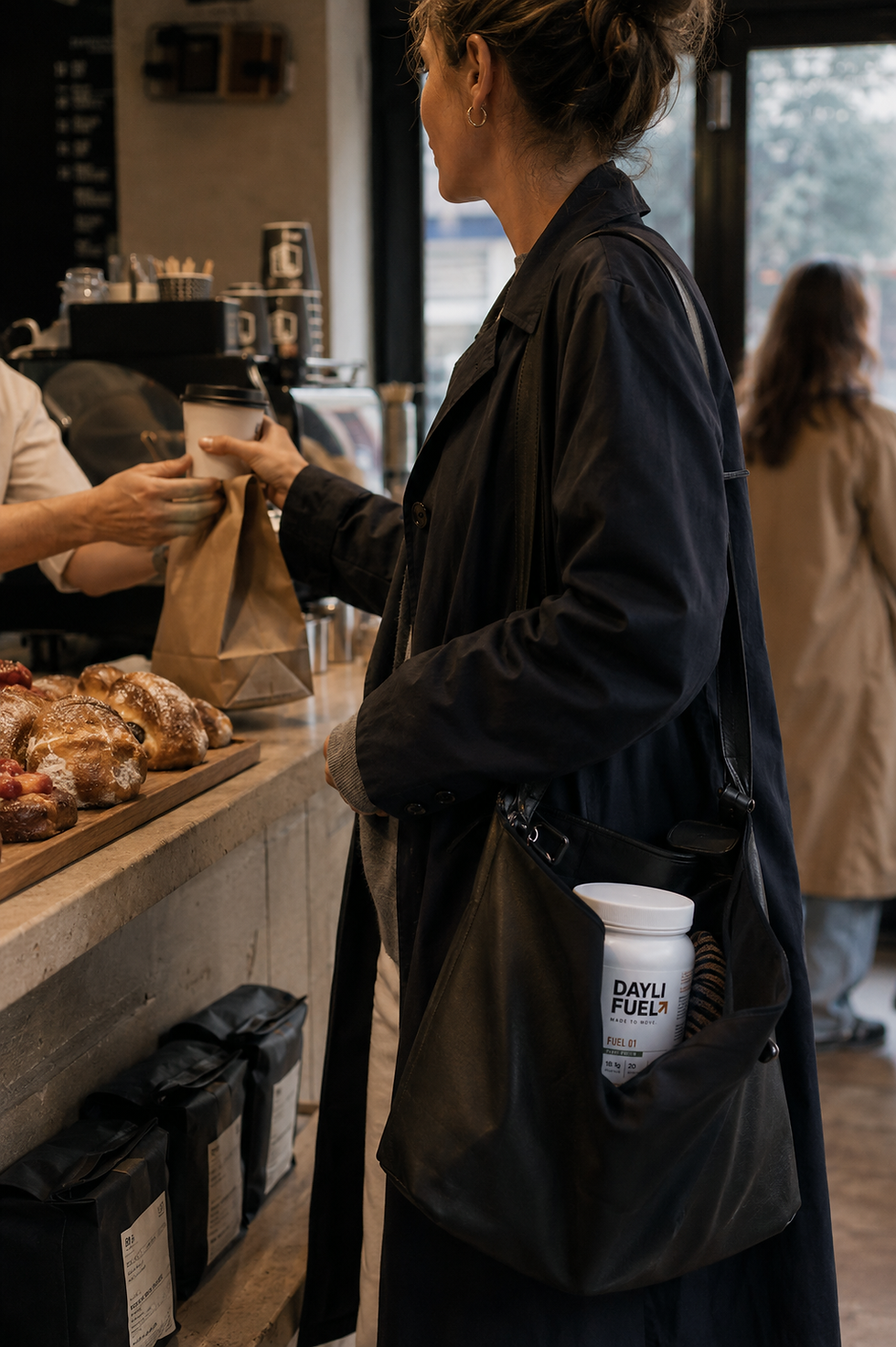 Thumbnail: Woman receiving a paper bag at a bakery counter, with a DAYLI FUEL tub in her shoulder bag's front pocket.