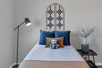 Small, cozy kids' room with an offset bed, oversized nightstand, and balanced height accents to maximize floor space and create a visually appealing, functional design.