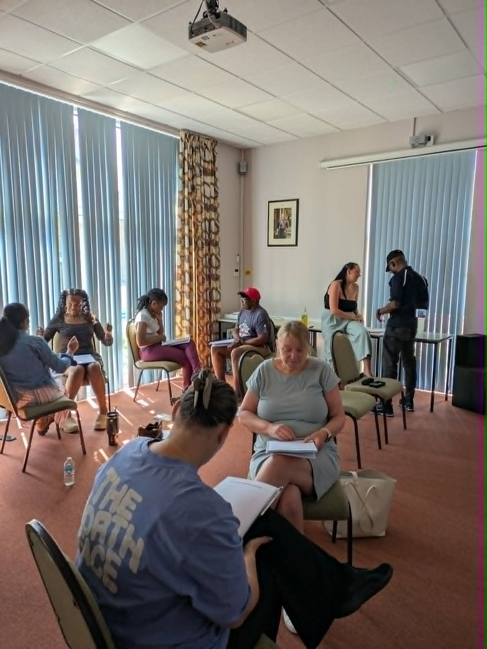A group of support workers from Enable and Support, Yeovil, in a meeting room, practising their Makaton signing in small groups