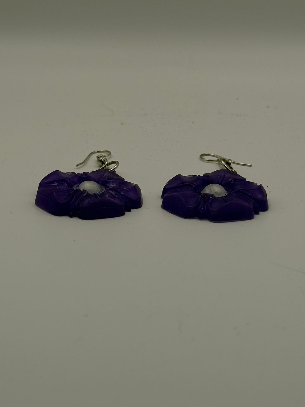 Thumbnail: Side profile of handmade purple resin flower earrings showing thickness and sculpted petal detail.