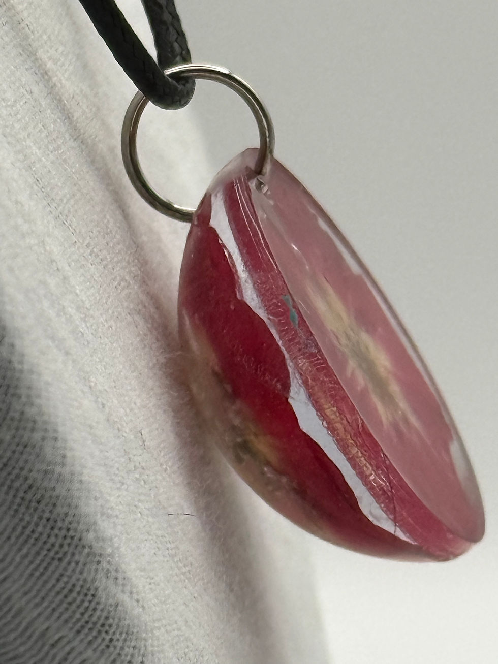 Thumbnail: Side view of domed resin pendant showing depth and embedded red flower detail