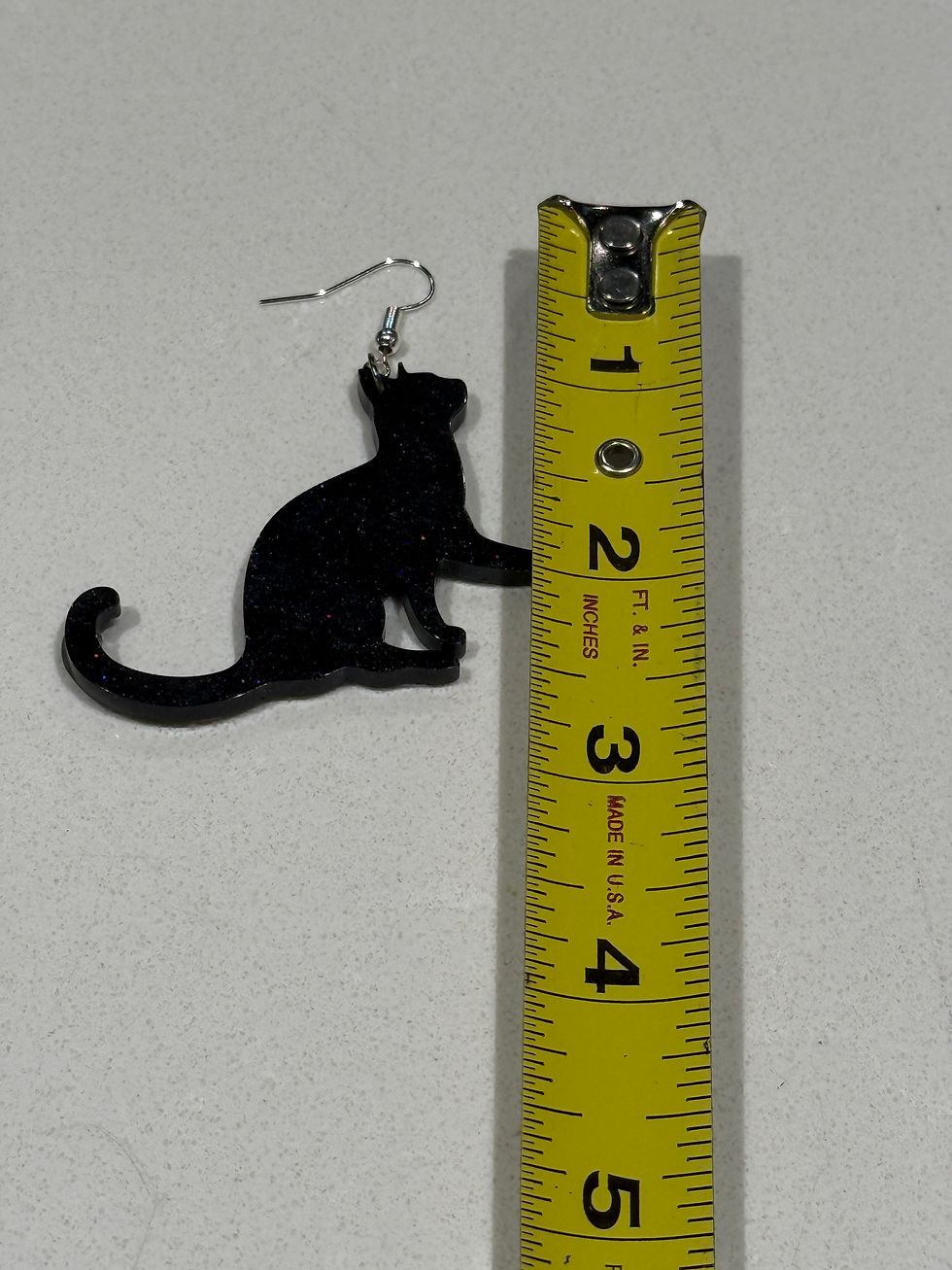 Thumbnail: Black cat resin earring next to measuring tape showing approximately 2 inches